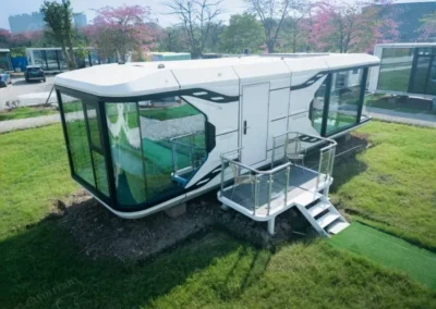 BAUSTADT Capsule House Model E8 exterior angled view with panoramic glass walls and entrance deck